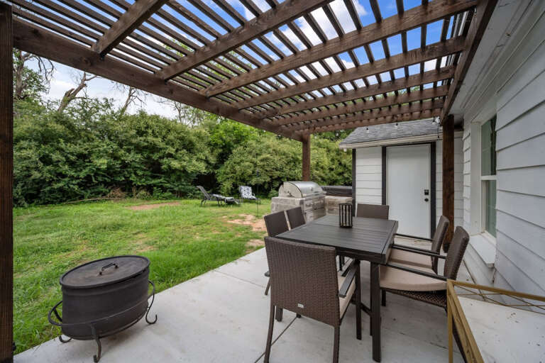 Backyard patio and outdoor dining area with grill and view toward hot tub area