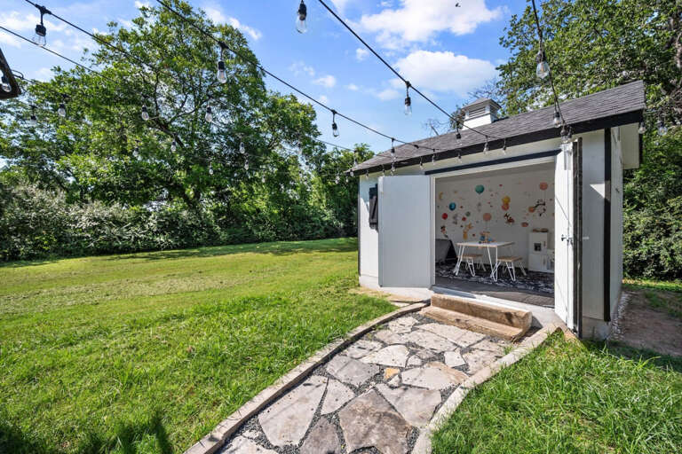 Walkway to outdoor children's playroom with AC and string lights above, child's play room
