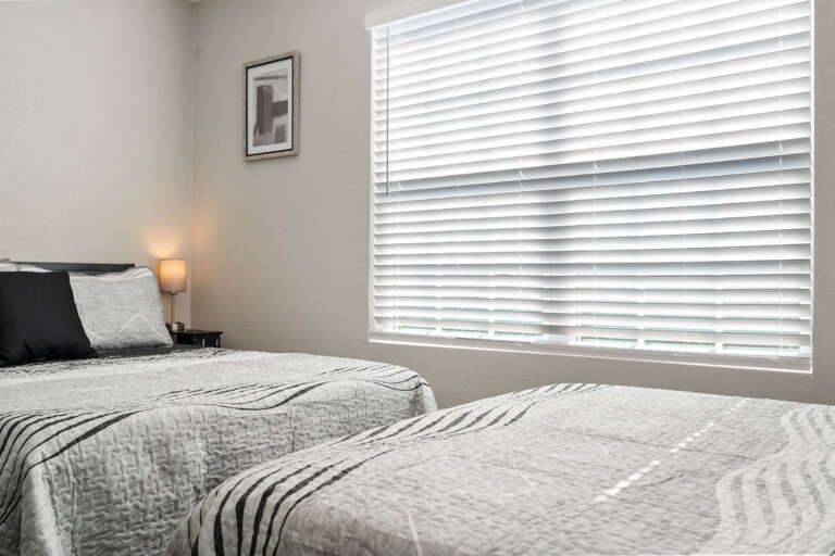 Third bedroom at front of house, with 2 Full-Sized beds, Smart Fire TV, ceiling fan, nightstands  with USB and Plugs, Dresser, luggage rack, and closet with hangers