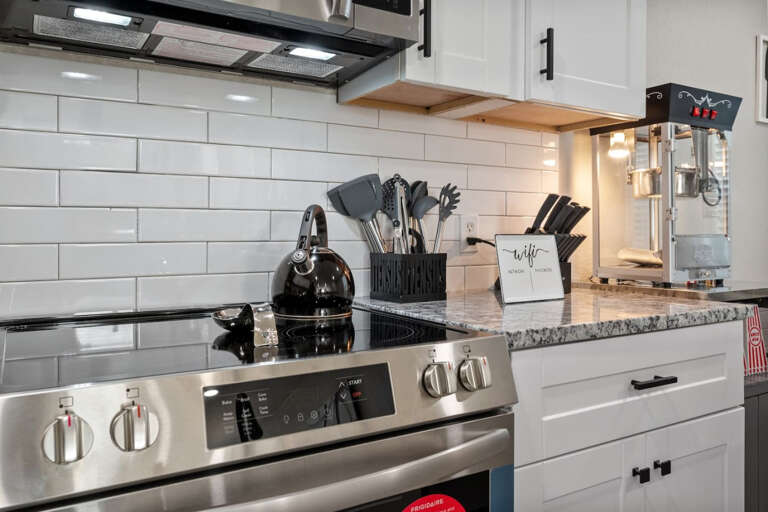 Full kitchen right countertop showing electric stove/oven range, kettle, utensils, and popcorn machine!