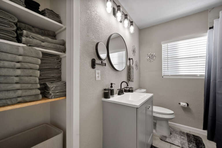 Secondary Full Bathroom with modern shower, vanity, toilet, lighted mounted makeup mirror for plenty of lighting, and linens with towels for your stay