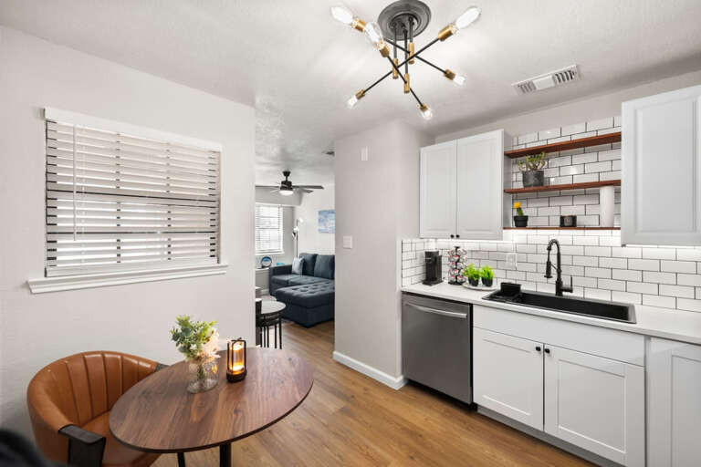 Kitchen showing 2 seating at dining, and into living area