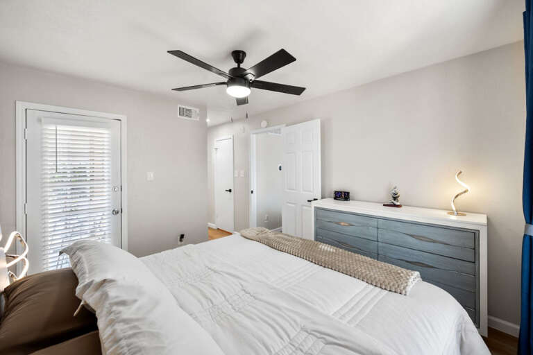 Primary Bedroom View of Balcony door, King Sized bed, and dresser