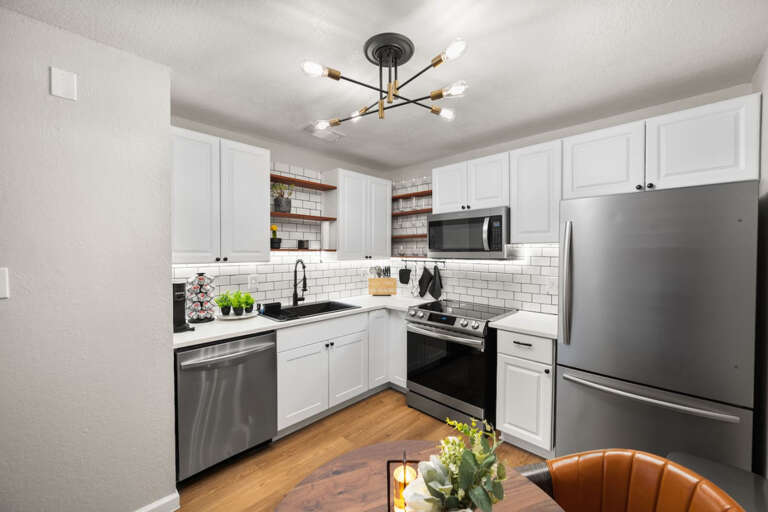 Fully stocked kitchen from dining area, showing all appliances, and coffee area