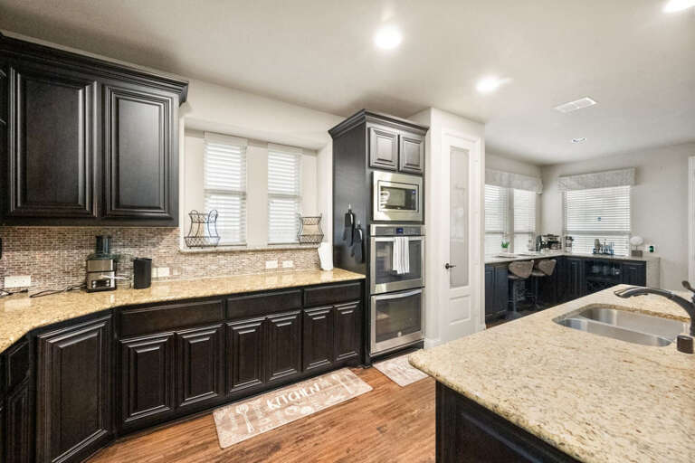 Downstairs full kitchen, showing island and countertop prep areas, microwave, double oven, pantry, looking back toward breakfast nook.