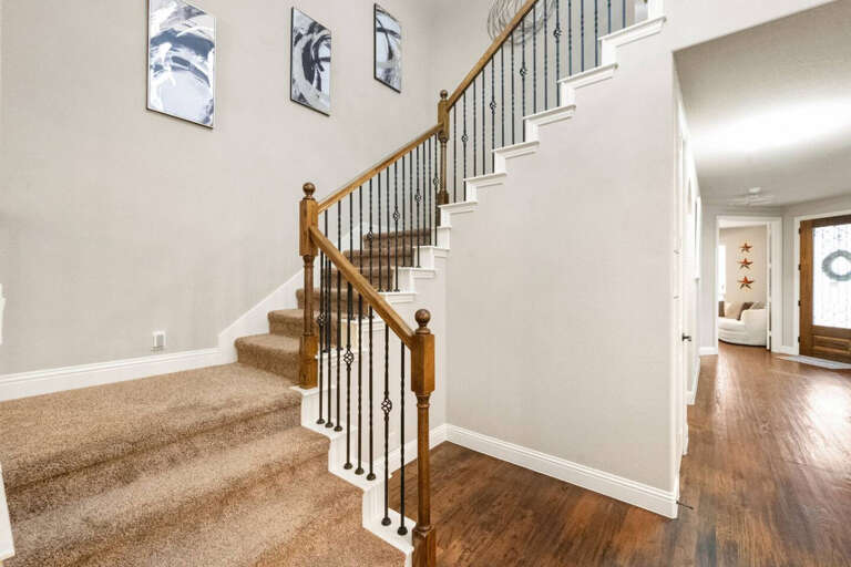 View of staircase going up to 2nd floor, and looking back to entryway area, toward dining room and office room with couch for sleeping.