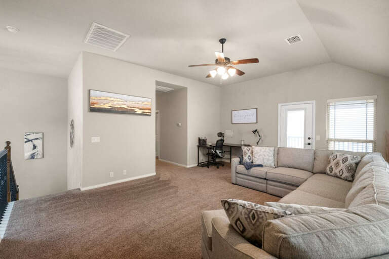 Upstairs living room area, showing sectional couch recliner closed, looking back toward staircase and hallway to bedrooms.