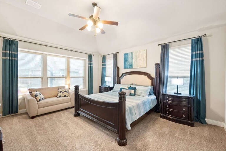 1st Floor Primary Bedroom, with King Bed, nightstands on each side, and sitting/reading area with love seat looking out window to backyard.