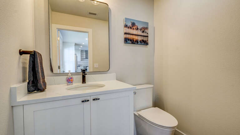 A bright half bath right between your pool and game room — the quick stop so nobody on the patio has to wander the whole house.