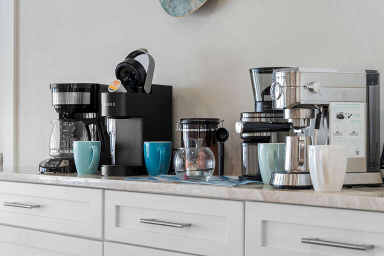 Your counter has a Keurig, Nespresso, and a drip coffee maker — every preference covered before the morning beach run.
