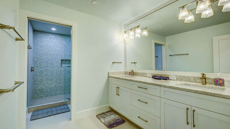 Double vanity and an open walk-in shower with blue tile — your bathroom handles two people getting ready at the same time, no arguments.