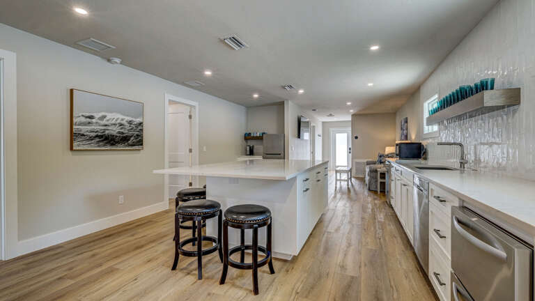 Your guest house has its own full kitchen — long counter run, island seating for five, and everything needed to keep both sides of your group fully independent.