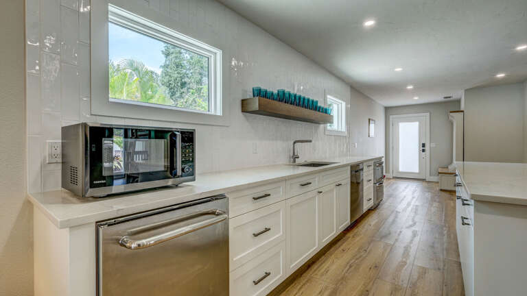 Your guest house kitchen doesn't cut corners — microwave, sink, beverage cooler, and clean cabinetry. Everything the main house has, just in a smaller footprint.