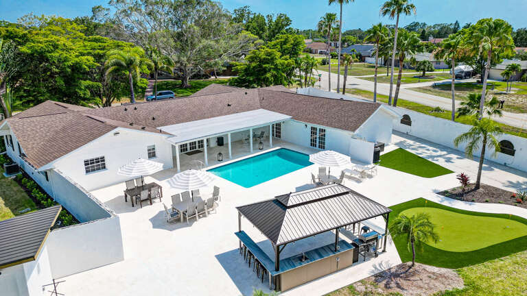 Your main house from the air — full pool patio with pergola, hot tub, and outdoor kitchen all laid out below you.