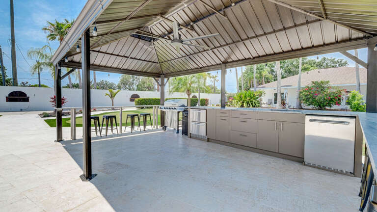 Outdoor kitchen offers shade, seating, and a fan to keep you cool while making a delicious meal on the grill.