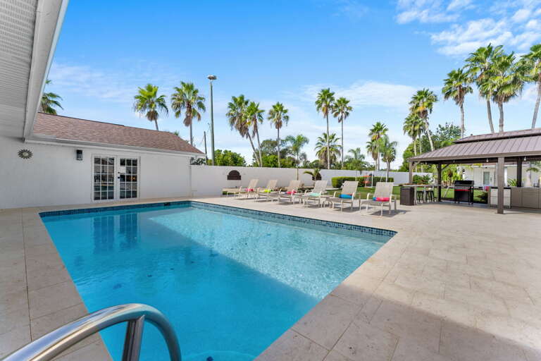 Your pool deck in full color — loungers out, turquoise water, and the outdoor kitchen visible in the back.