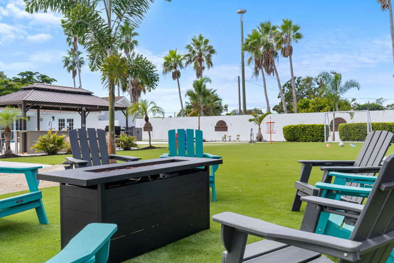 Pull your chair to the fire pit table and let the evening happen — the gazebo is lit behind you, palms swaying above, and nowhere you'd rather be right now.