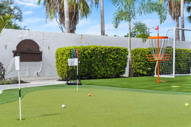 Your putting green has three holes and a disc golf basket in the corner — the flags are up and someone in your group will be out here before breakfast.