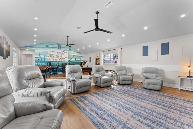 Your recliners face the pool table with the beach mural stretching the full back wall — the game room is set up and waiting before you walk in.