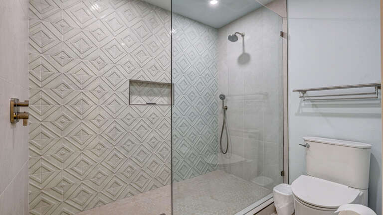 Your walk-in shower has a rainfall showerhead and floor-to-ceiling tile — the kind that earns its own five minutes after a long day at the beach.
