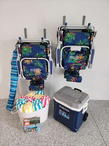 Beach chairs, striped towels, and a rolling cooler — all provided. Grab them and go, no extra stop needed on the way to the sand.