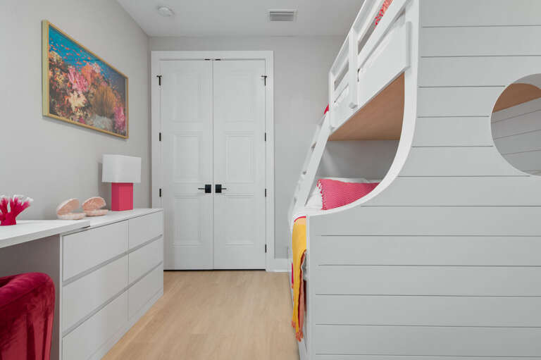 The bunk room from the doorway — desk, coral reef art on the wall, the kind of room kids talk about on the drive home.