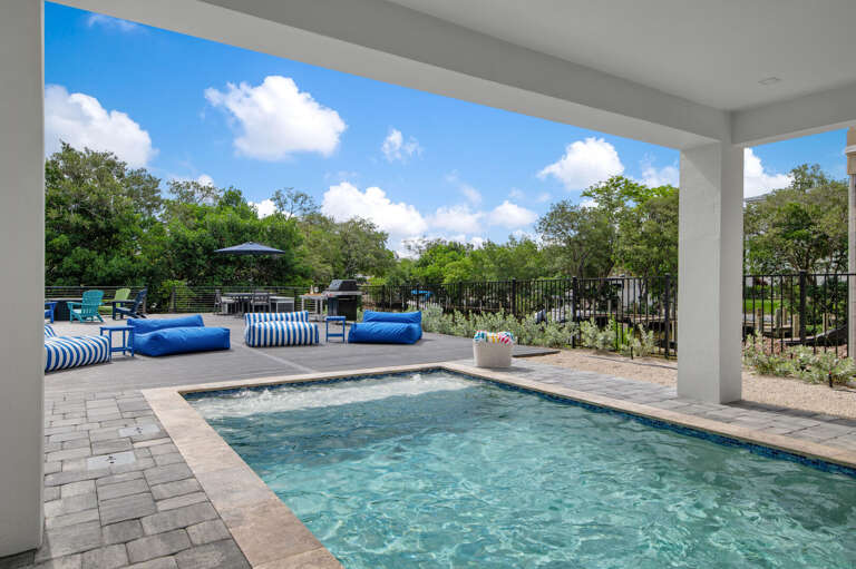 You'll start every morning out here — cool water, striped loungers under the patio overhang, and nothing on the agenda until you decide otherwise.