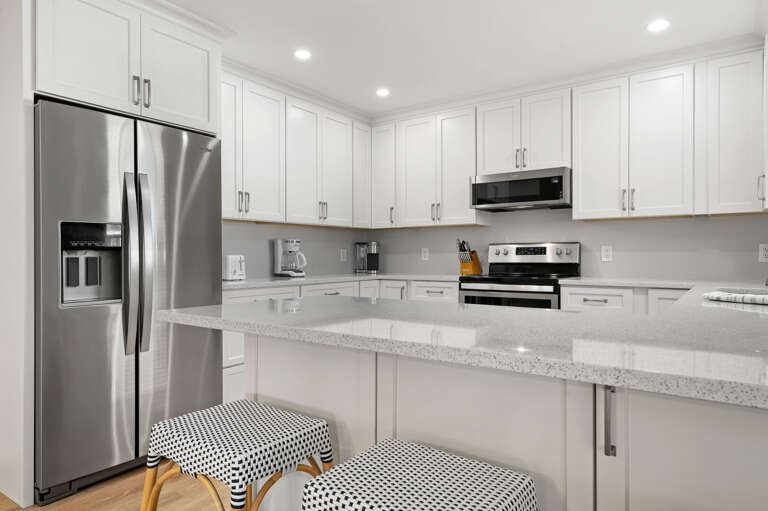 Stock the fridge and claim your counter space — quartz tops, white shaker cabinets, and everything you need for a real Florida dinner.