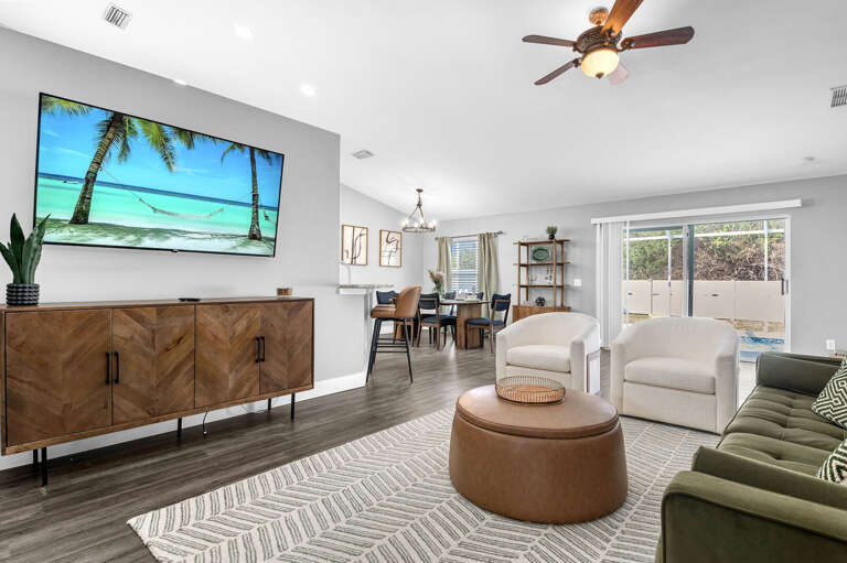 Your main hangout space is anchored by a deep green sofa, two swivel accent chairs, and a smart TV — settle in and put something good on.