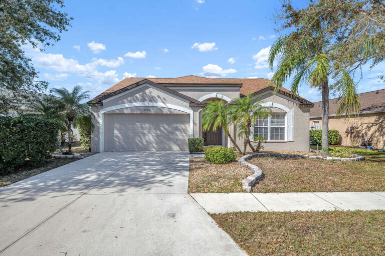 Pull into your own driveway and feel the vacation start — single-story home with a 2-car garage and those Florida palm trees setting the scene.