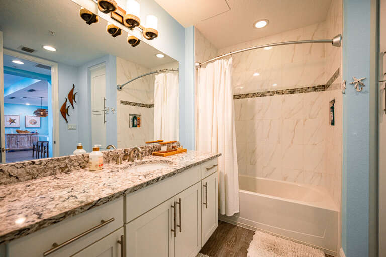 Use a second bathroom that actually looks designed — coastal fish tiles and granite vanity make it feel finished, not forgotten.
