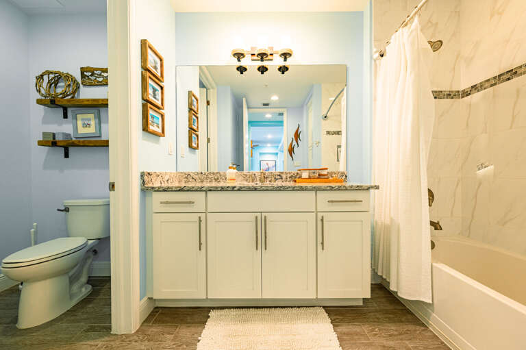 Find a spotless second bathroom stocked and ready — single vanity, granite counter, and a full tub-shower for your guests.