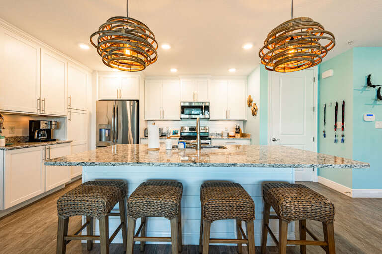 Pull a stool up to the island, pour a glass of wine, and keep the cook company — the rattan pendants set exactly the right mood.