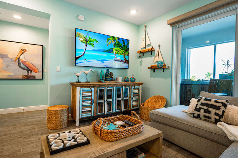 Sink into the sectional for a night in — the TV corner is set up and the coastal art makes it feel like the right kind of evening.