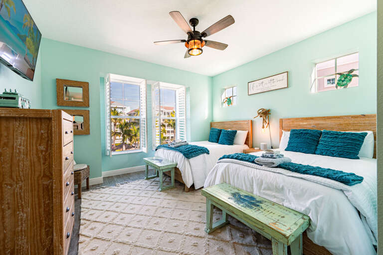 Sleep four guests in real comfort — the second bedroom's queen beds, ceiling fan, and coastal vibe make it feel like its own retreat.