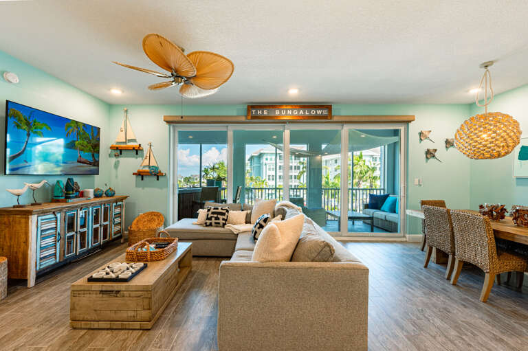 Step into a living room with coastal light and balcony access right off the back — the kind of space that earns its keep on a beach trip.