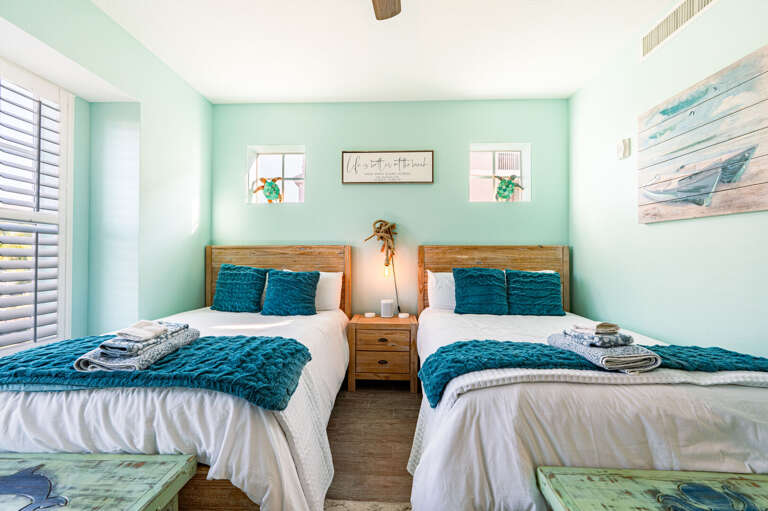 Walk into a second bedroom that's genuinely finished — coastal art, quality bedding, and enough floor space to actually breathe.