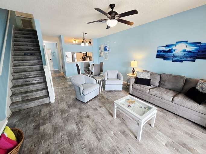 Your whole downstairs — sofa, dining, kitchen, staircase — open and ready for the group to spread out.