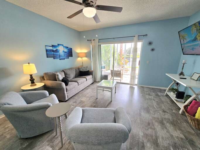 Ease onto the gray sectional, ceiling fan turning overhead, patio door cracked open to the Florida air.
