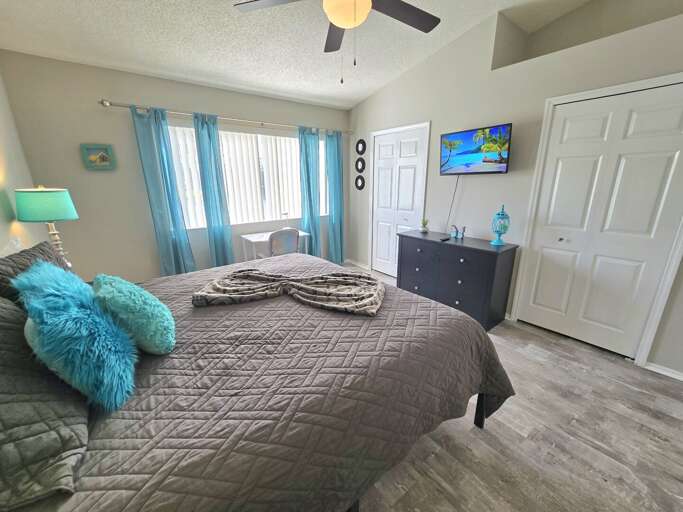 Your guest bedroom has a wall-mounted TV and teal curtains — everyone gets a private, comfortable space.