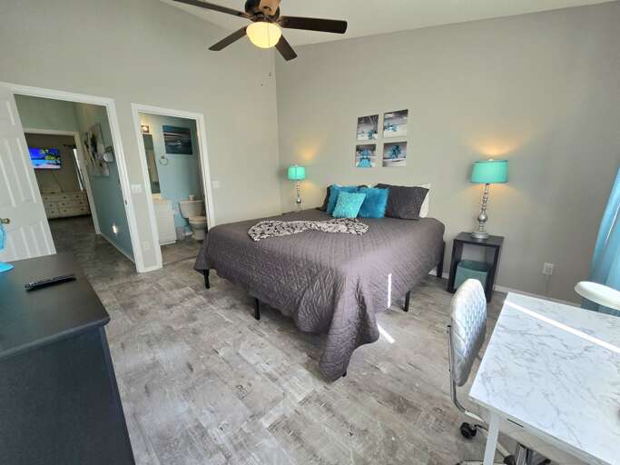 Step into the second bedroom from the doorway — teal lamps, ceiling fan, and easy access to the bath.