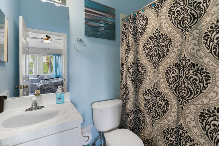 Step into the coastal blue bathroom — a damask curtain, white vanity, and everything clean and ready.