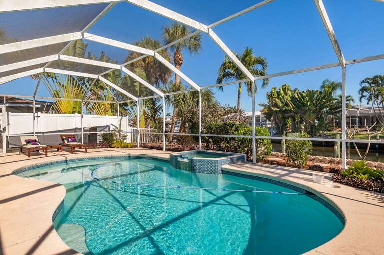 Step past the lounge chairs toward the screen and you will catch your first glimpse of the canal behind the property.