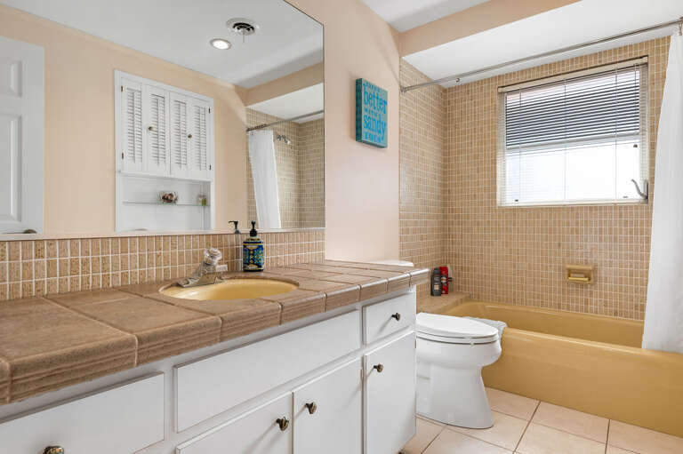 Step into the shared hall bathroom to rinse off — full tub-shower combo keeps the setup practical for a busy beach week.