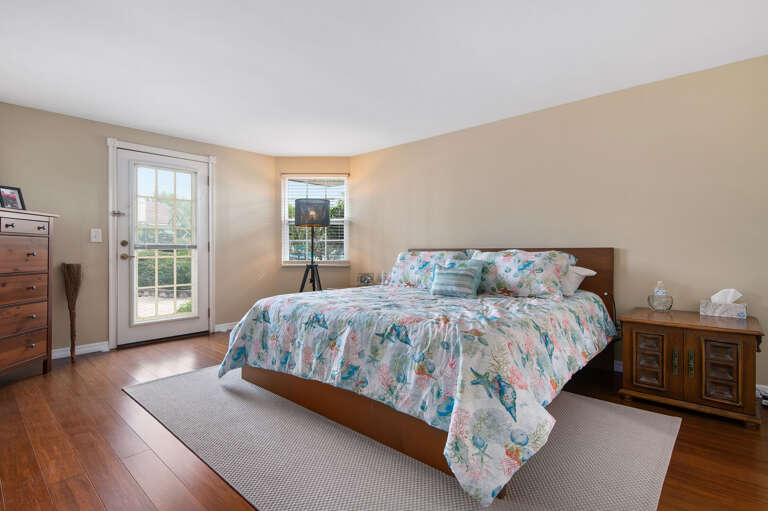 Wake up in the primary king bedroom with hardwood floors, floral bedding, and a glass door that opens directly to the outside — fresh air is one step away.