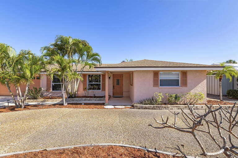 Walk up to classic Florida curb appeal — shuttered windows, mature palms, and clean lines that set the tone before you even open the door.