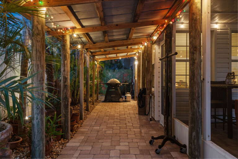 Hang out in the breezeway after dinner with the kamado still warm and the string lights doing their thing — this covered outdoor stretch is everyone's favorite place to linger.