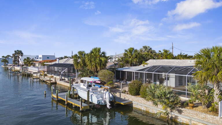 Paddle back from the canal and look at the house from the water — the private dock, the screened enclosure, and the tropical backyard all come into view exactly like this.