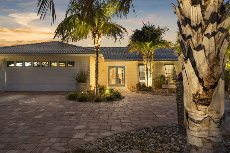 Park, unload, and look back at this front facade before you go inside — the uplighted palms and sunset sky make the arrival feel like a scene from the Florida vacation brochure you actually booked.