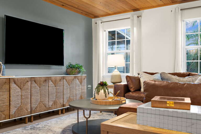 Settle in for a movie night on the deep couch and let everyone pile on — the smart TV handles streaming, the fan keeps it cool, and the room is dark enough to actually feel the film.